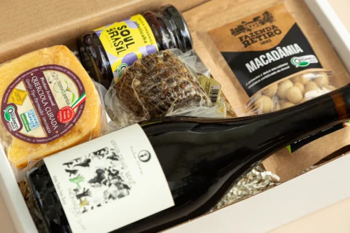 kit de presente sustentável com: vinho orgânico, queijo, socol, macadâmia e geleia jabuticaba. Imagem com aproximação dos elementos.