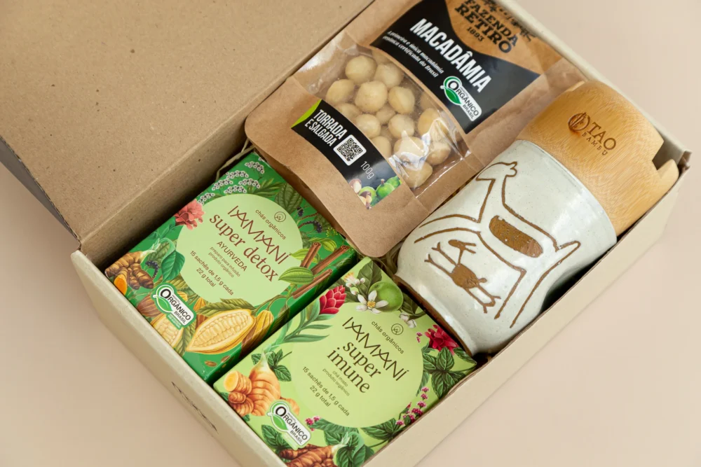 kit de presente sustentável com: chás orgânicos com mel White Wods, macadâmias, copo serra capivara e apoio celular.Imagem com aproximação dos elementos.
